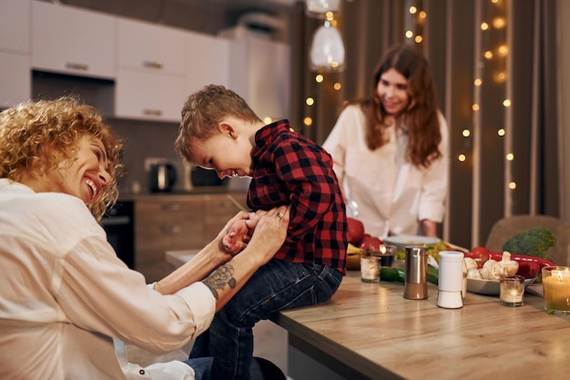 Une famille heureuse de mère fille et fils est dans la cuisine le soir