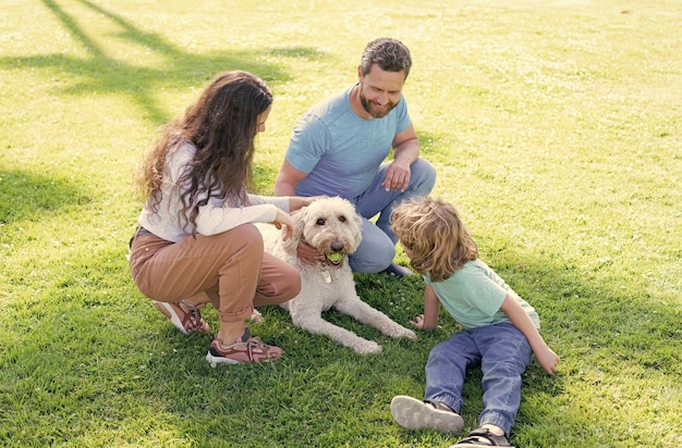 Famille heureuse de mère père et fils jouant avec un chien dans le parc sur la famille de l'herbe verte