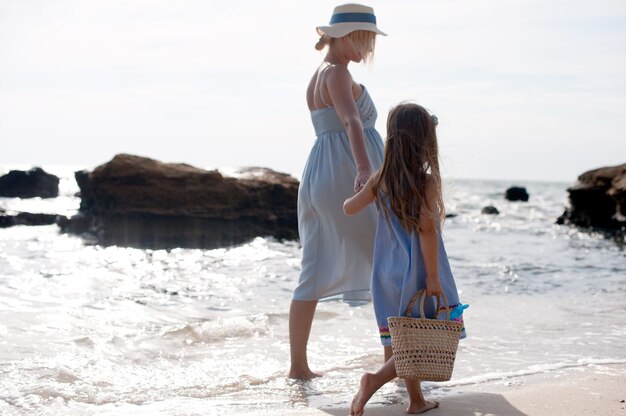 Famille heureuse - mère et petite fille faisant de la randonnée près de la mer