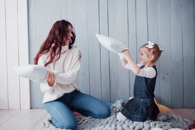 Famille heureuse La mère et son enfant se battent des oreillers. Jeux de famille heureux