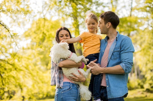 Famille heureuse avec mignon chien bichon dans le parc