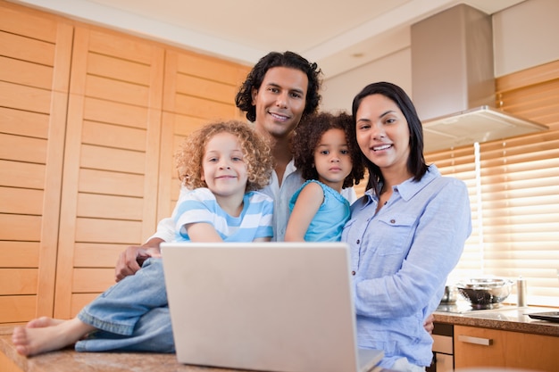 Famille heureuse avec ordinateur portable debout dans la cuisine ensemble