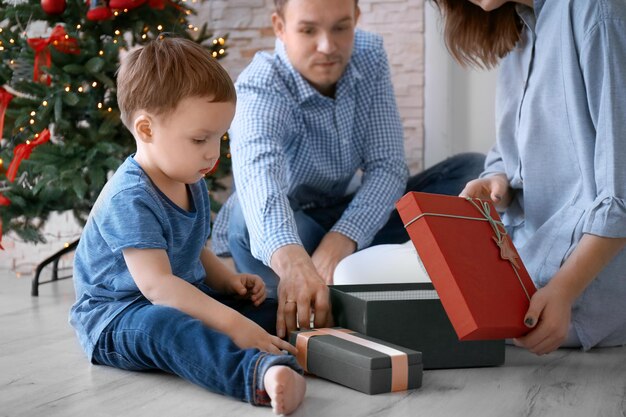 Famille heureuse ouvrant des coffrets cadeaux près de l'arbre de Noël à la maison