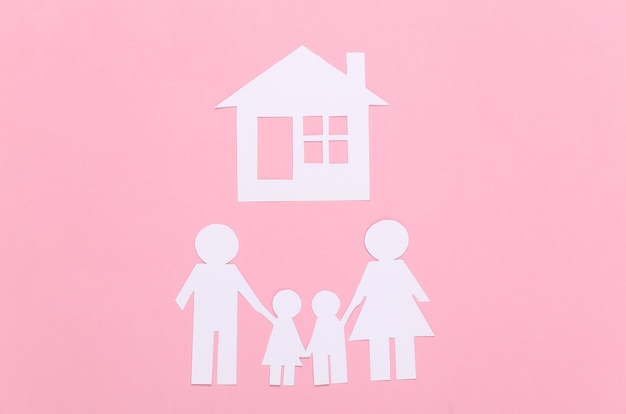 Famille heureuse de papier avec la maison sur le pastel rose