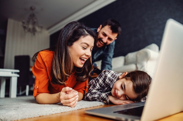 Famille heureuse passant du bon temps ensemble à la maison. Ils utilisent un ordinateur portable pour regarder des vidéos en ligne.