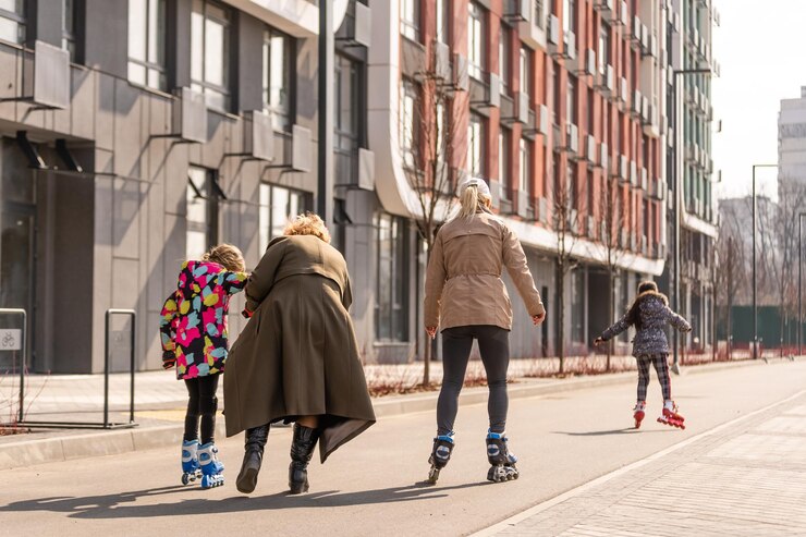 Une famille heureuse en patins à roulettes, grand-mère apprend à deux petites-filles à faire du patin à roulettes