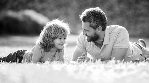 Famille heureuse de père et fils garçon se détendre dans l'amitié de l'herbe verte du parc d'été