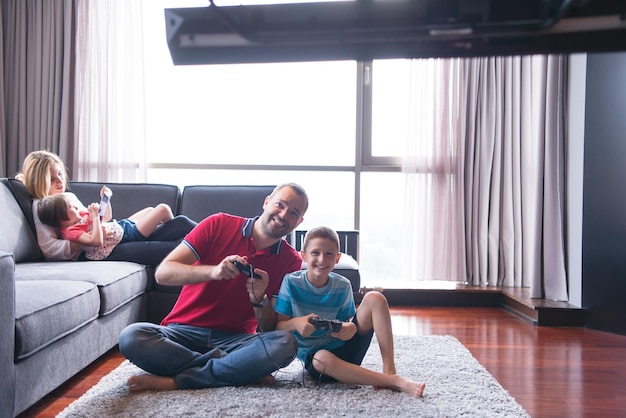 Famille heureuse. Père, mère et enfants jouant à un jeu vidéo Père et fils jouant à des jeux vidéo ensemble sur le sol