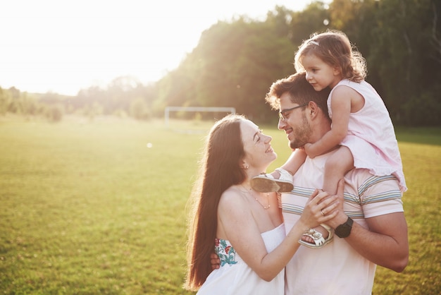 Famille heureuse, père de mère et fille de bébé dans la nature au coucher du soleil