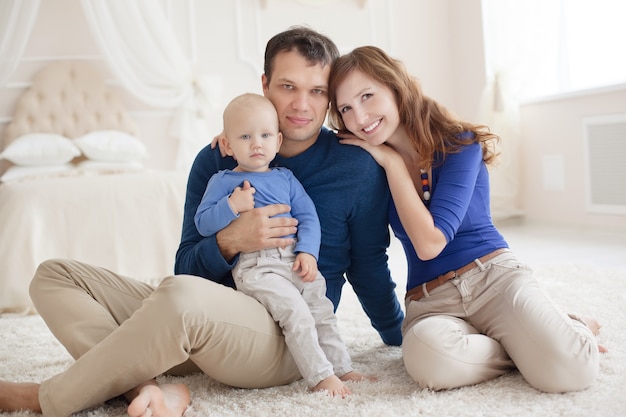 Famille heureuse avec petit bébé jouant sur le tapis