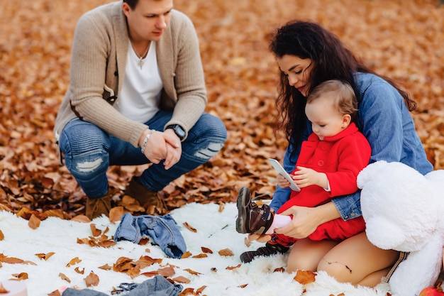 Famille heureuse avec petit enfant mignon dans le parc sur une feuille jaune avec grosse citrouille en automne