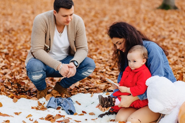 Famille heureuse avec petit enfant mignon dans le parc sur une feuille jaune avec grosse citrouille en automne