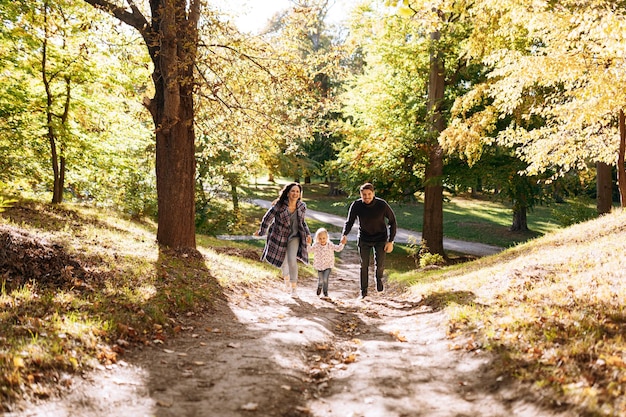 Famille heureuse avec petite fille dans les loisirs de plein air du parc d'automne