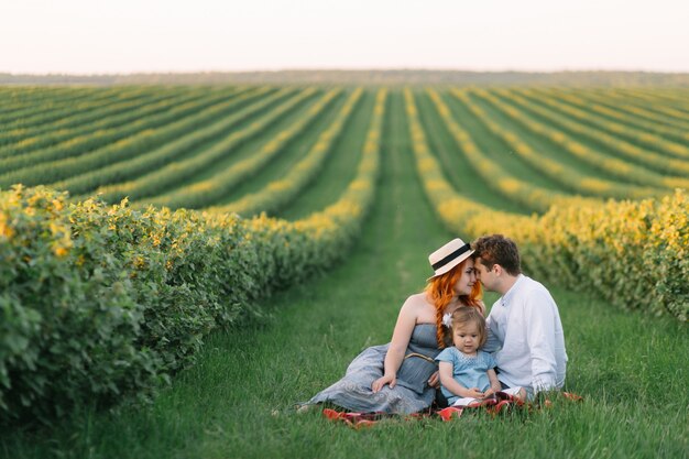 Famille heureuse avec petite fille passer du temps ensemble dans le champ ensoleillé