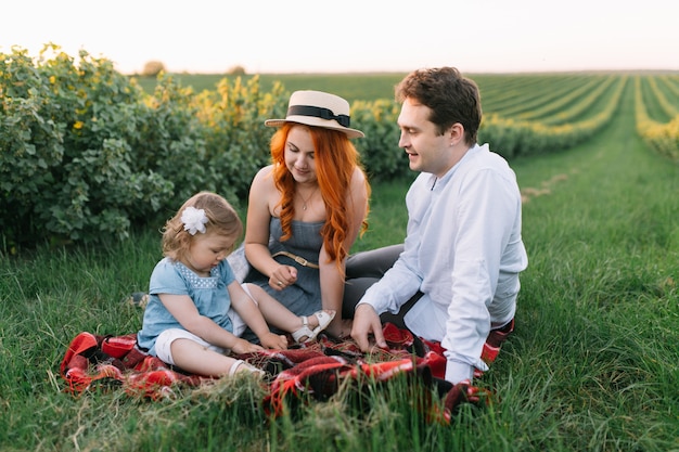 Famille heureuse avec petite fille passer du temps ensemble dans le champ ensoleillé