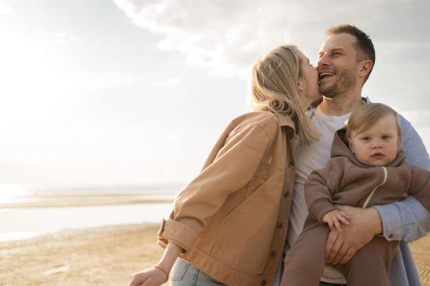 Famille heureuse petite fille souriante jouant sur la plage jeunes parents