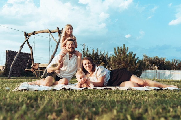 Famille heureuse et petits enfants sur une couverture dans l'herbe en été