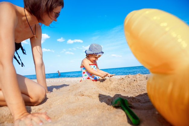 Famille heureuse sur la plage mère et bébé fille en mer