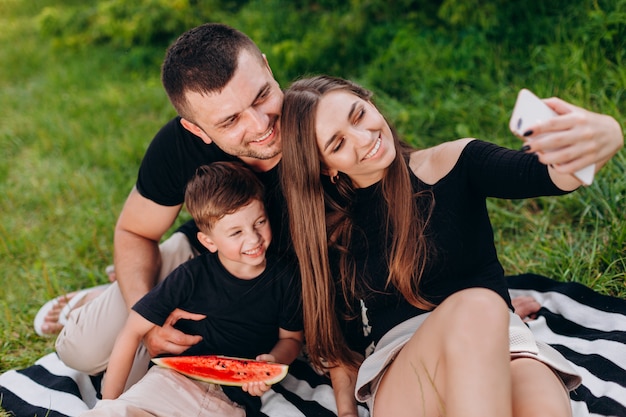 Famille heureuse prendre une photo selfie lors d'un pique-nique dans le parc agrandi.