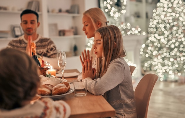 La famille heureuse priant à la table de Noël
