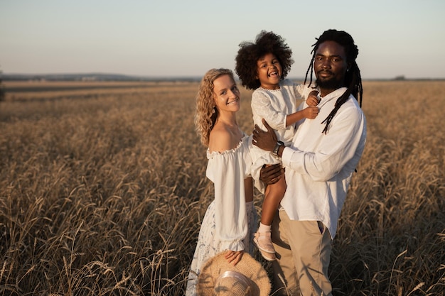 Une famille heureuse en promenade dans un champ d'été au coucher du soleil.