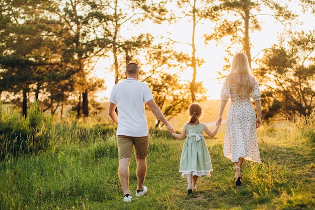 Famille heureuse en promenade d'été Mère père et filles marchant dans le parc et profitant de la belle nature