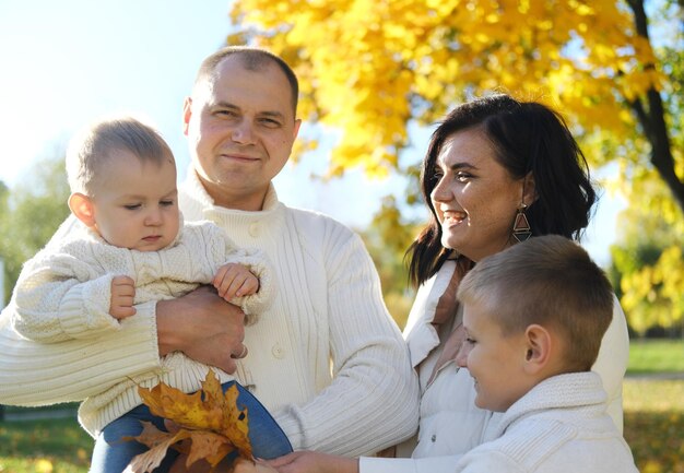 Photo une famille heureuse de quatre personnes passe du temps dans le parc d'automne.