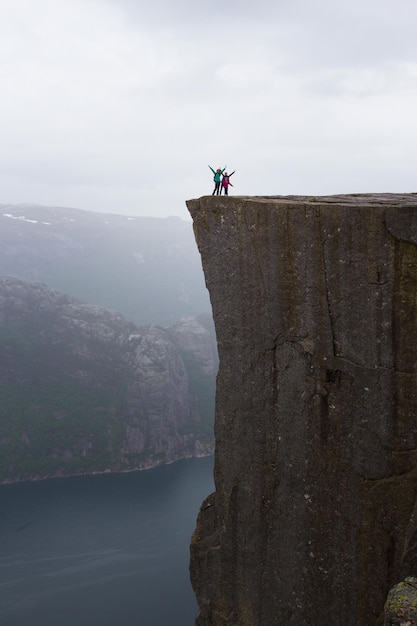 Famille heureuse - randonneur maman et filles debout sur Preikestolen et regardant les montagnes par temps couvert, Preikestolen - célèbre falaise des montagnes norvégiennes