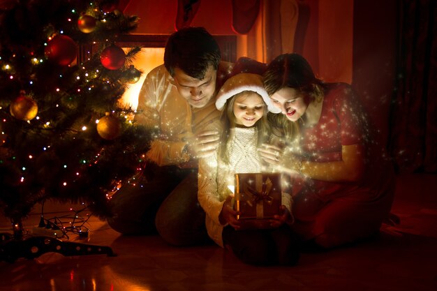 Famille heureuse regardant à l'intérieur de la boîte-cadeau magique de Noël