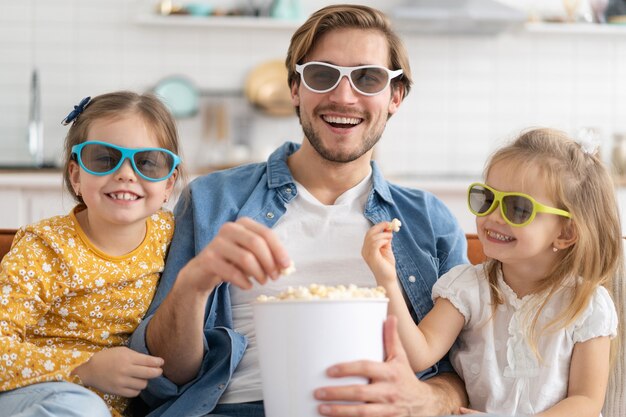 Famille heureuse regardant la télévision à la maison et mangeant du pop-corn.