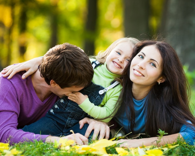 Famille heureuse s'amusant contre l'arrière-plan flou des feuilles d'automne