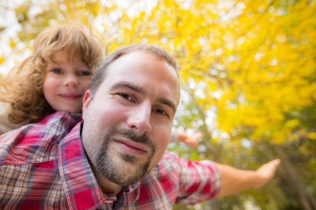 Famille heureuse s'amusant à l'extérieur dans le parc d'automne sur fond de feuilles floues jaunes