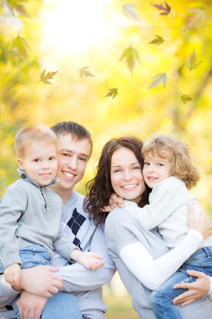 Famille heureuse s'amusant à l'extérieur dans le parc d'automne sur fond de feuilles floues