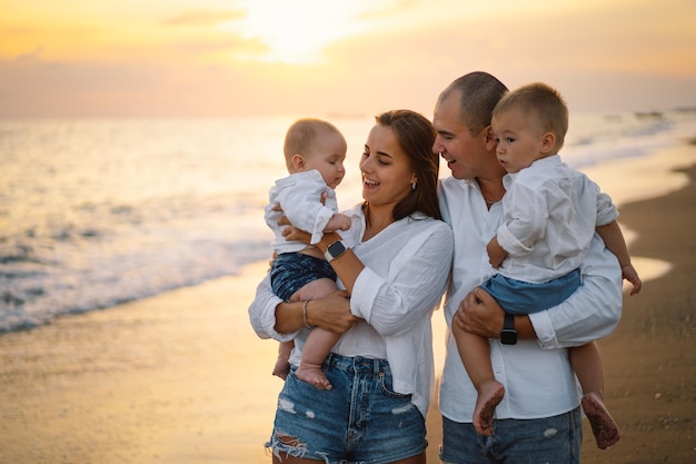 Famille heureuse s'amusant à jouer à la plage pendant les vacances d'été sur la plage Famille heureuse et concept de vacances Paysage marin au coucher du soleil avec un beau ciel Famille sur la plage