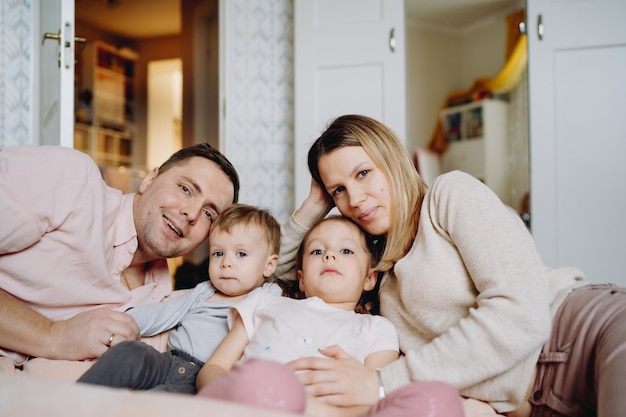 famille heureuse s'amusant à la maison étreignant leurs enfants allongés sur le sol dans la chambre d'enfant