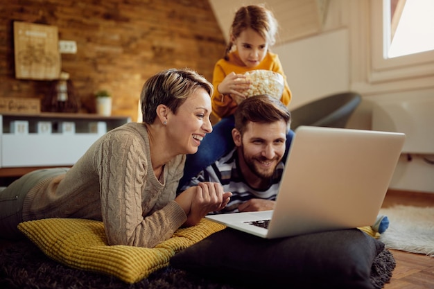 Famille heureuse s'amusant tout en utilisant un ordinateur portable à la maison