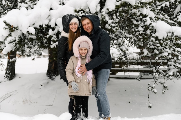 Une famille heureuse s'amuse dans la forêt d'hiver. Mère, père et fille jouant avec la neige. Profiter de passer du temps ensemble. Notion de famille