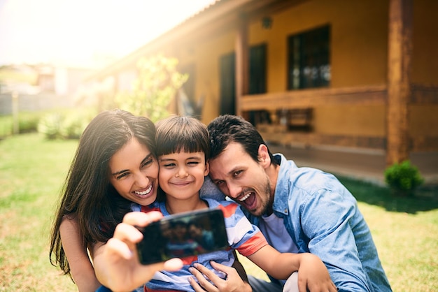 Une famille heureuse se détend et sourit pour une photo de selfie ou une photo de profil dans un vlog de médias sociaux à l'extérieur de la maison