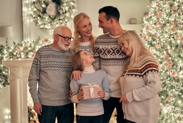 La famille heureuse se tenant sur le fond d'arbre de Noël