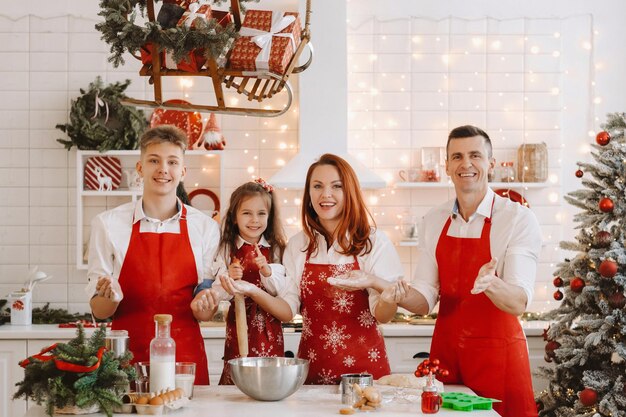 Une famille heureuse se tient dans la cuisine de Noël et prépare la pâte pour faire des biscuits