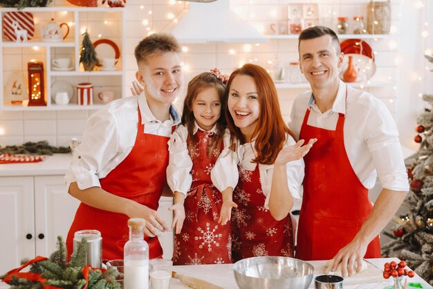 Une famille heureuse se tient dans la cuisine de Noël et prépare de la pâte pour faire des biscuits.