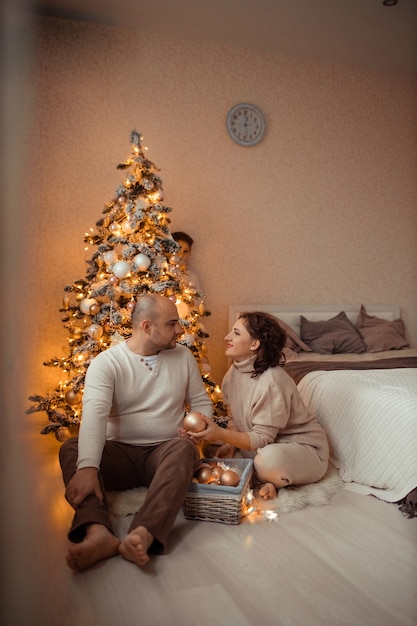 famille heureuse avec son fils sous l'arbre de noël dans la chambre