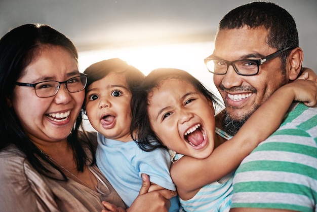 Une famille heureuse tous ensemble Portrait d'une jeune famille joyeuse debout ensemble tout en regardant la caméra à l'intérieur de la maison pendant la journée