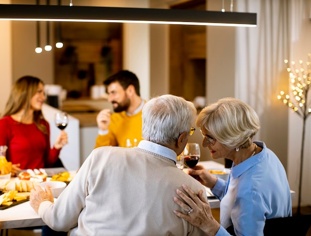 Famille heureuse en train de dîner avec du vin rouge à la maison