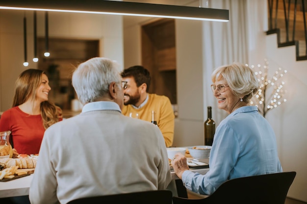 Famille heureuse en train de dîner avec du vin rouge à la maison