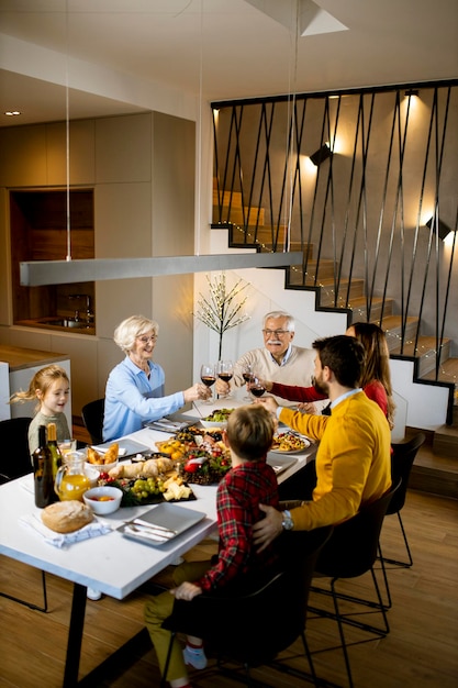 Famille heureuse en train de dîner avec du vin rouge à la maison