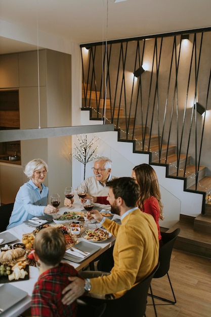 Famille heureuse en train de dîner avec du vin rouge à la maison