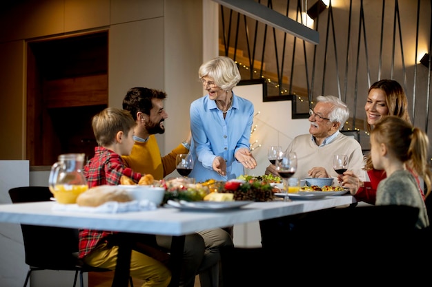 Famille heureuse en train de dîner avec du vin rouge à la maison