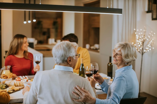 Famille heureuse en train de dîner avec du vin rouge à la maison