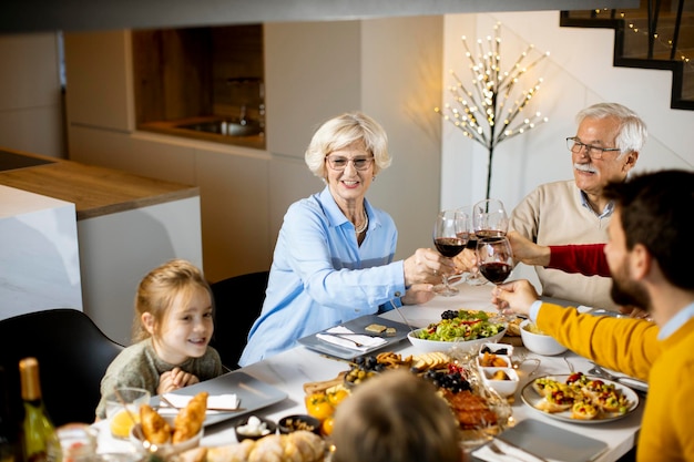 Famille heureuse en train de dîner avec du vin rouge à la maison